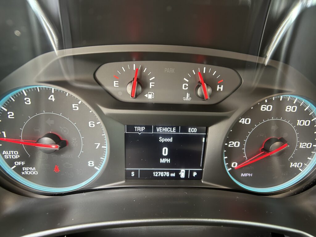 Car instrument cluster view showing fuel gauge, temperature gauge, and speedometer with digital odometer (127,676 mi) and trip info on screen.