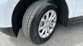Close-up of a car wheel and tire mounted on a white vehicle, showing the tread pattern and alloy rim in view.