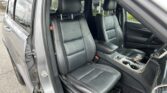 Interior of a right-hand-drive SUV with black leather seats featuring red contrast stitching; front seats and center console visible.