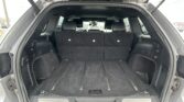 SUV cargo area with third-row seats up, open rear hatch showing spacious black interior and cargo rails on the floor