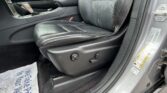 Front interior of a car showing black leather seats with red stitching, center console, and gear shifter by the door edge.