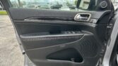 Interior of a car door panel with power window controls and chrome handle; side mirror and a parking lot scene outside the window