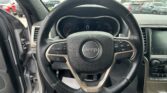 View from the driver's seat of a Jeep, showing the steering wheel and instrument cluster in a parked car in a parking lot.