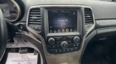 Front interior view of a car with the center touchscreen showing 'Climate Off', flanked by air vents and parked cars outside the windshield.