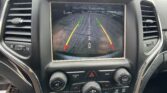 Dashboard screen showing rearview camera guide lines over a parking lot; 'Check Entire Surroundings' shown on screen.
