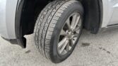 Close-up of a car's front wheel with a treaded tire and silver alloy rim, inside the wheel well.