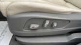 Beige leather car seat with side power-adjustment controls; center console and armrest visible in the background.