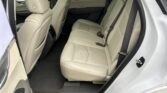 Rear interior of a white SUV featuring beige leather seats and three-point seat belts.