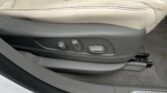 Beige leather car seat with power adjustment switches on the lower front edge, inside a vehicle interior.