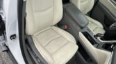 Beige leather car seats inside the front cabin with a center console and light-colored door panels visible from the open front door