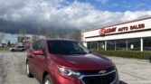 Red Chevrolet SUV in a dealership lot with EZ Loan Auto Sales building in the background and a blue sky above.
