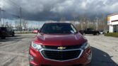Red Chevrolet SUV photographed from the front in a parking lot with a cloudy sky overhead.