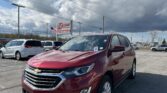 Red Chevrolet SUV in a car dealership lot with EZ Loan Auto Sales sign and other vehicles under a cloudy sky.