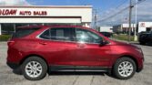 Red Chevrolet Equinox parked in front of an auto dealership under a bright blue sky with power lines overhead.