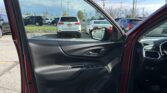 Front passenger door is open, showing a black interior with a view of a crowded parking lot and blue sky outside.