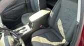 Inside view of a red Chevrolet: driver and front passenger seats with quilted fabric, center console, and steering wheel visible.