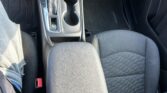 Center console in a car: gear shifter, two cup holders, and a closed armrest area between front seats.