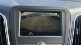 Driver's perspective: car dashboard and rearview camera screen showing a parking lot with guiding yellow and red lines behind the vehicle.