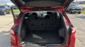 Rear hatch open on a red Chevrolet SUV, revealing a roomy cargo area with a rubber floor mat and folded rear seats nearby.