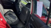 Open rear door of a red SUV showing black fabric back seats and front seats; a white document is taped to the front passenger window.
