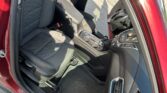 Inside a red car showing the driver's seat, front passenger seat, steering wheel, and center console with the door open.