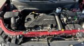 Front view of a red car with the hood open, showing the ECOTEC engine cover, battery, and coolant reservoir in the engine bay.