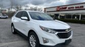 White Chevrolet Equinox parked in a car lot in front of EZ Loan Auto Sales on a cloudy day with a red sign on the building signage visible