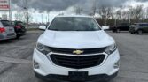 Front view of a white Chevrolet SUV parked in a lot with dark stormy clouds overhead.