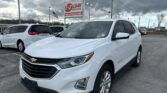 White Chevrolet SUV parked in a dealership lot with an EZ Loan Auto Sales sign and a cloudy sky in the background.