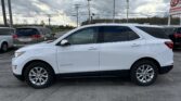 White Chevrolet Equinox SUV parked in a lot, shown in profile under a cloudy sky with power lines overhead.