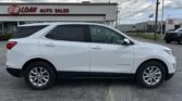 White SUV (Equinox) parked in front of E-Z Loan Auto Sales dealership, with cloudy sky above and other cars in the lot nearby.