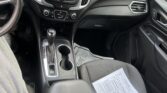 Interior view from driver's seat showing center touchscreen, climate controls, gear shifter, and cupholders with a paper on the passenger seat
