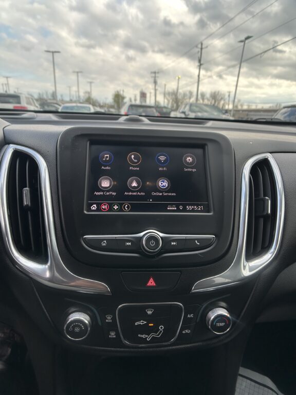 Car interior with a center touchscreen displaying app icons (Audio, Phone, Wi‑Fi) and climate controls below.