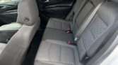 Back seat area of a car showing quilted gray upholstery, headrests, and three seat belts in a dark interior.