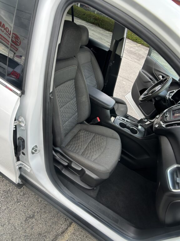 Front car interior with the driver’s seat and center console visible, door open showing steering wheel and dashboard.