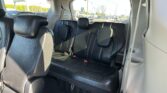 View of the back row in a SUV with black leather seats, headrests, and visible seat belts; outside street traffic seen through the windows.