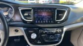 Car dashboard with touchscreen showing Classic Rock on 96.9 FM, parked in a lot outside the car.