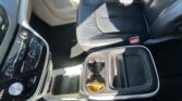 Front passenger seat and center console in a black leather car interior, cup holder visible by the seat belt buckle.