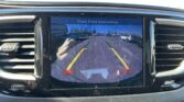 Car rearview screen showing parking guide lines over a parking lot; text reads 'Check Entire Surroundings'