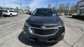 Front view of a dark gray Chevrolet SUV in a sunny dealership lot with other cars in the background.