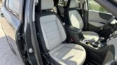 Interior of a car showing the front seats with light gray quilted upholstery and black trim, with the driver's door open.