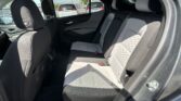 Rear passenger seat area of a modern car, gray quilted upholstery, visible seat belts and headrests, with the door and window frames in view.