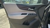 Interior of a car door panel with a chrome door handle, armrest, and window/lock controls; outside parking lot visible through the window.
