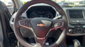 Photo from the driver’s seat showing a Chevrolet steering wheel, instrument cluster, and center touchscreen in a car interior.