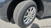Close-up of a car tire mounted on a silver alloy wheel, with the dark SUV body and wheel well visible.