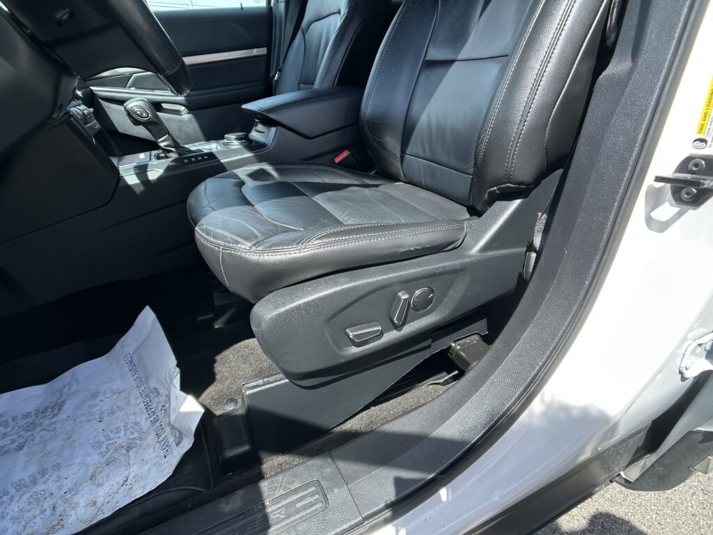 Driver's seat and center console in a black leather car interior, with gear selector and door panel visible.