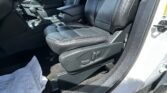 Driver's seat and center console in a black leather car interior, with gear selector and door panel visible.