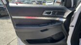 Interior of a car door panel with window/mirror controls and chrome door handle, parking lot visible through window.