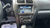 Car interior focusing on the center infotainment screen and climate controls, with a gear shift and steering wheel visible.