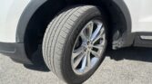 Close-up of a white SUV's front wheel and tire, showing Goodyear branding and alloy rim inside the wheel well